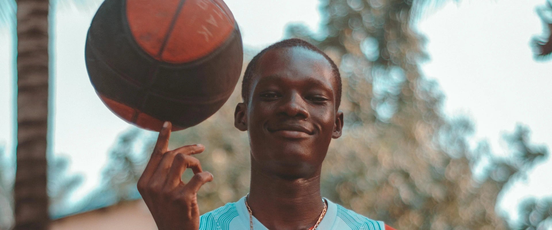 Un jeune du centre fait tourner un ballon de basket sur son doigt.