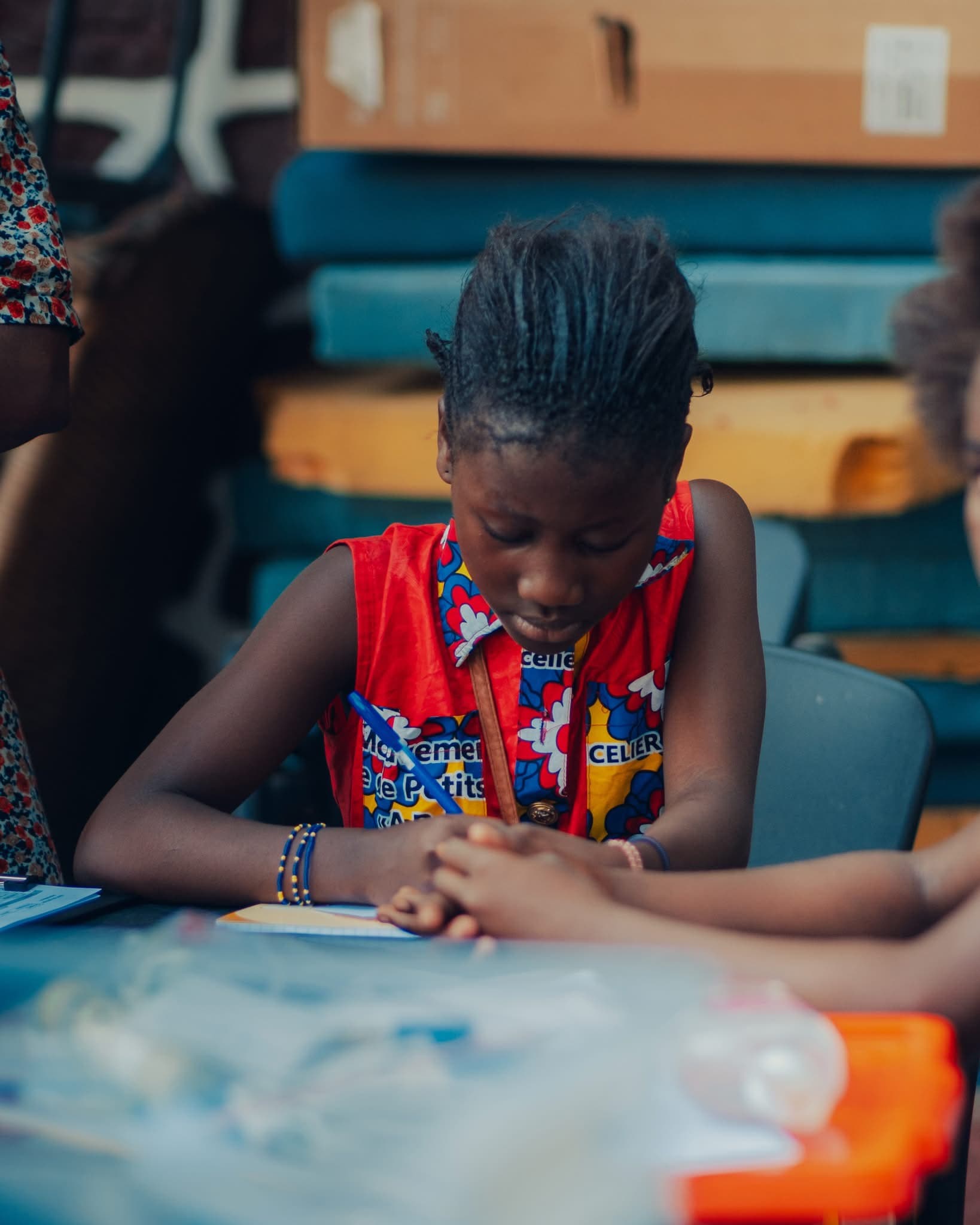 Une jeune fille écrit dans son cahier pendant un atelier.